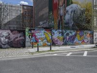 the street in front of the graffiti covered building is empty and empty, but has two rows