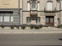 a building on a side walk with an entrance and flower boxes in front of the entrance