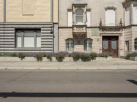 a building on a side walk with an entrance and flower boxes in front of the entrance