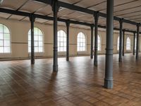 large floor with columns, windows and wood floors in an old building that has no walls