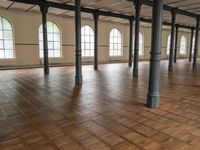 large floor with columns, windows and wood floors in an old building that has no walls