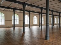 large floor with columns, windows and wood floors in an old building that has no walls