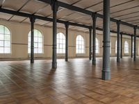 large floor with columns, windows and wood floors in an old building that has no walls