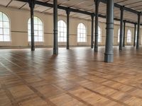 large floor with columns, windows and wood floors in an old building that has no walls