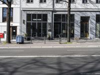 a bike sits in front of a building near a bike rack and a sidewalk, on which are no cars