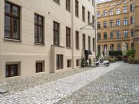 the ground is made of stones and bricks with white furniture and chairs outside it with an umbrella