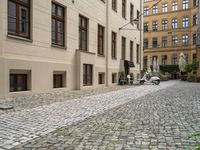 the ground is made of stones and bricks with white furniture and chairs outside it with an umbrella