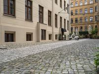 the ground is made of stones and bricks with white furniture and chairs outside it with an umbrella