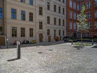 a green shrub near a gray building and a brick walkway with a bicycle rack in it