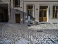 an empty parking lot with plants in the ground and on the side of the building, there is an enclosed area and windows