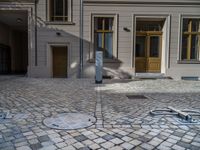 an empty parking lot with plants in the ground and on the side of the building, there is an enclosed area and windows