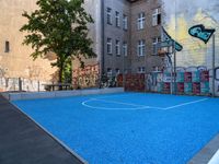 a basketball court in the middle of a street with graffitti on it and graffiti all over it