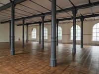 a large empty room with windows and wooden floors with columns that are leaning down to the left