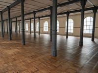 a large empty room with windows and wooden floors with columns that are leaning down to the left