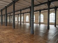 a large empty room with windows and wooden floors with columns that are leaning down to the left