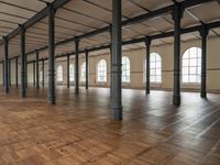 a large empty room with windows and wooden floors with columns that are leaning down to the left