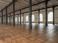 a large empty room with windows and wooden floors with columns that are leaning down to the left