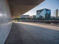 a skateboarder riding on a cement ramp next to a city street under a bridge