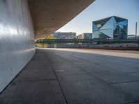 a skateboarder riding on a cement ramp next to a city street under a bridge