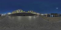 a panorama lensed view of a city at night taken from the ground with its reflection in the water