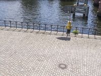 a bench sits by a river next to a metal fence and stairs way with a fire hydrant