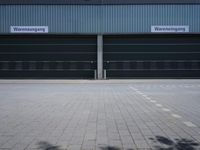 two garages that are closed and attached to each other with signs on them sitting in front of a blue and cloudy sky