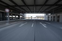 a highway with cars and buildings in a warehouse yard with light posts at the end