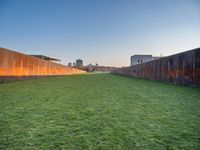 this grass field has been cut short to cover the area in the distance, and it is a grassy area next to an old building