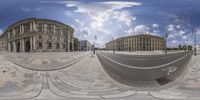 360 view in front of a round building with blue sky and clouds above it and with two bicycles parked in the foreground