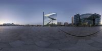 a big reflective silver object outside a city center setting on a cloudy day with buildings