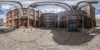 the view of an outdoor street from a fisheye lens of a shopping district, surrounded by red brick buildings