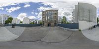 a fish eye lens of skateboarders riding the ramp at a skate park with tall buildings in the background