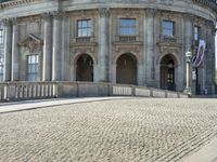 there is a man skateboarding on the paved street and an old building on the background