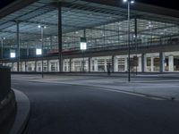 a long exposure image of a night view of an airport terminal building with a street and car lights