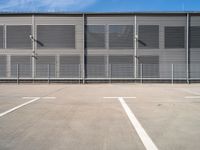 an empty parking lot with some benches next to the large building on the right side