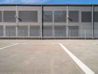 an empty parking lot with some benches next to the large building on the right side