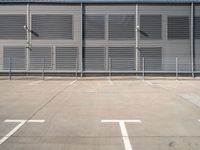 an empty parking lot with some benches next to the large building on the right side