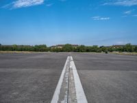 a deserted paved airfield with a long, straight line going to the left side of the frame