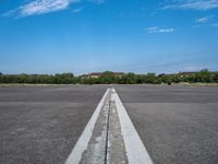 a deserted paved airfield with a long, straight line going to the left side of the frame