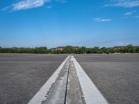 a deserted paved airfield with a long, straight line going to the left side of the frame