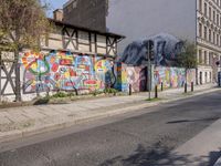 some graffiti on a building near the street and some buildings in the background with a woman walking