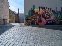 a street art mural with horse drawn carriage in the center of it, and a brick road leading to a building