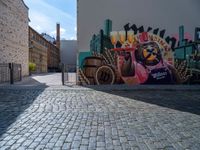 a street art mural with horse drawn carriage in the center of it, and a brick road leading to a building