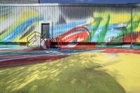 colorful mural painted on the wall of a building near a playground and park area with children playing outside