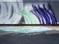 an artistic street art with a blue green white and black painting on a building wall