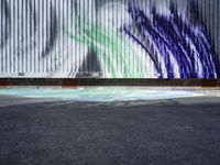 an artistic street art with a blue green white and black painting on a building wall