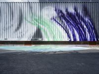 an artistic street art with a blue green white and black painting on a building wall