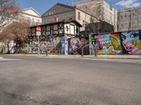 an empty street with colorful graffiti on the wall in the city setting, on a clear day