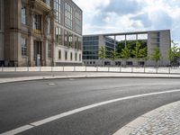 a street scene, with a fence along the road and building in the background in this image,