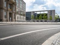 a street scene, with a fence along the road and building in the background in this image,